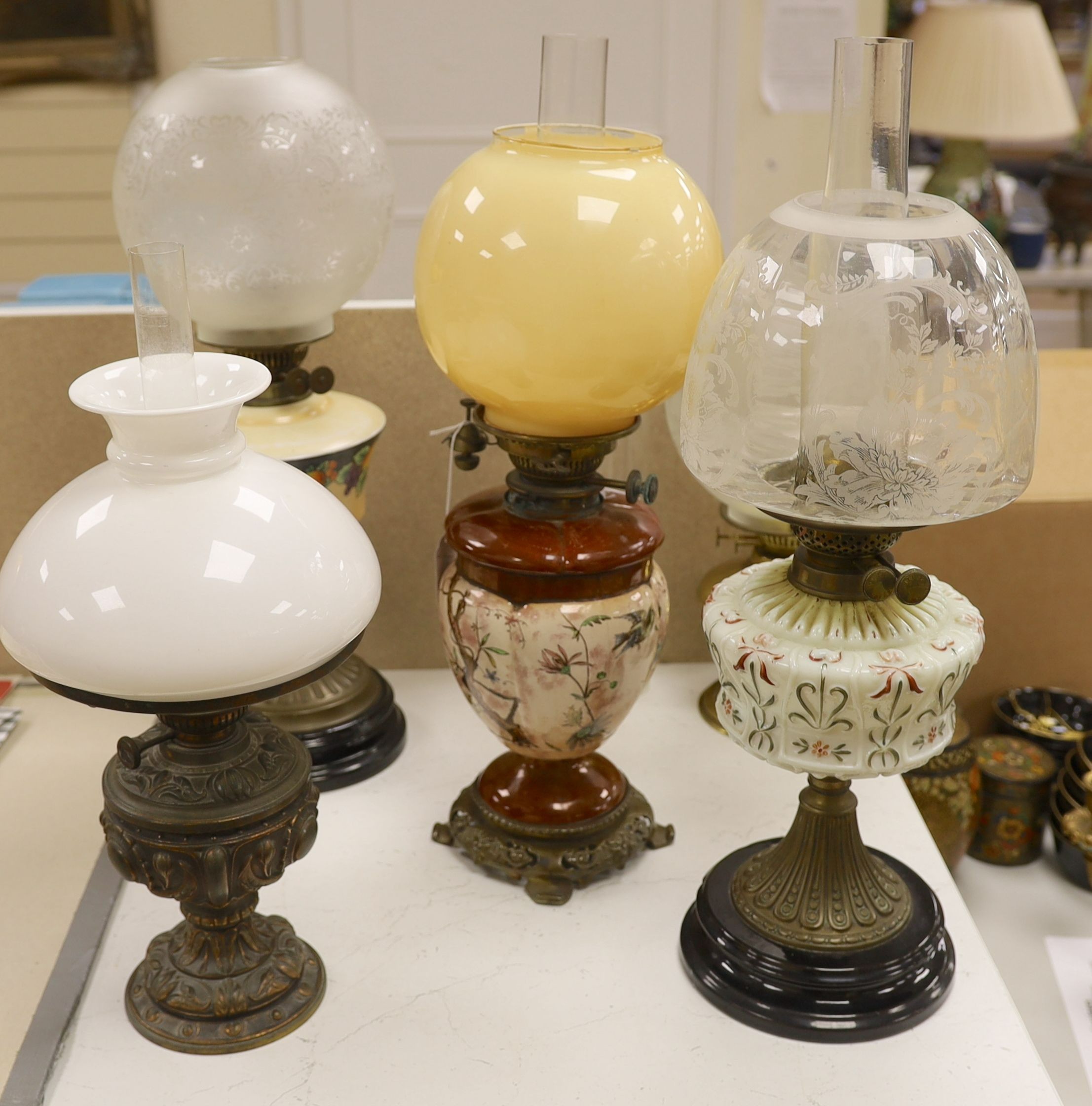 A Doulton style pottery oil lamp and four other glass and brass oil lamps, tallest 54 cms including glass shade.